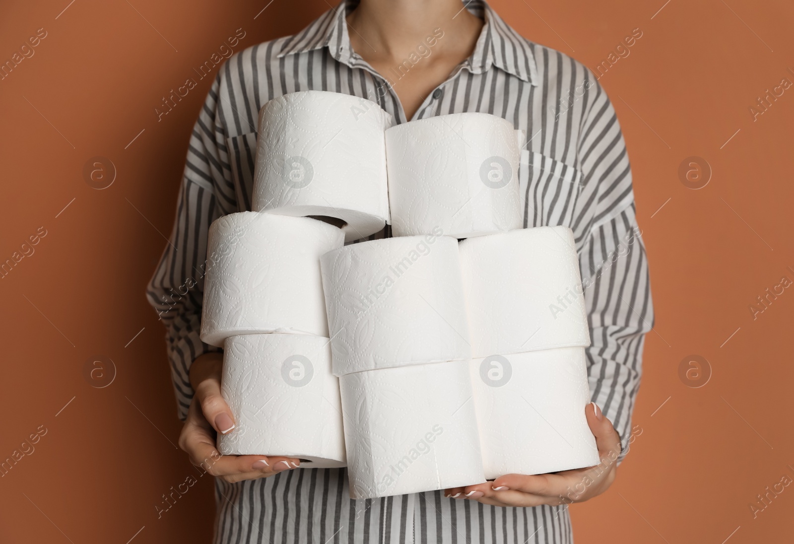 Photo of Woman with heap of toilet paper rolls on brown background, closeup