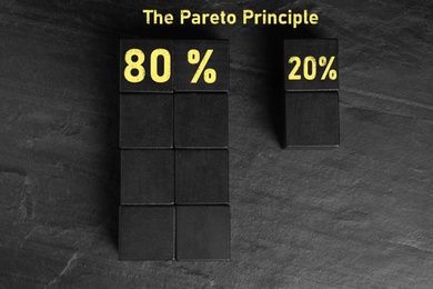 Image of Flat lay composition with cubes on black slate background. Pareto principle concept