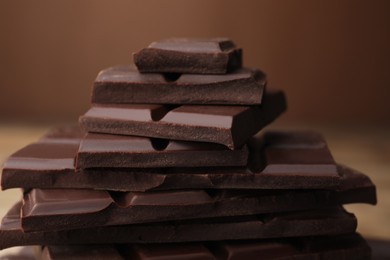 Photo of Pieces of tasty chocolate on blurred background, closeup