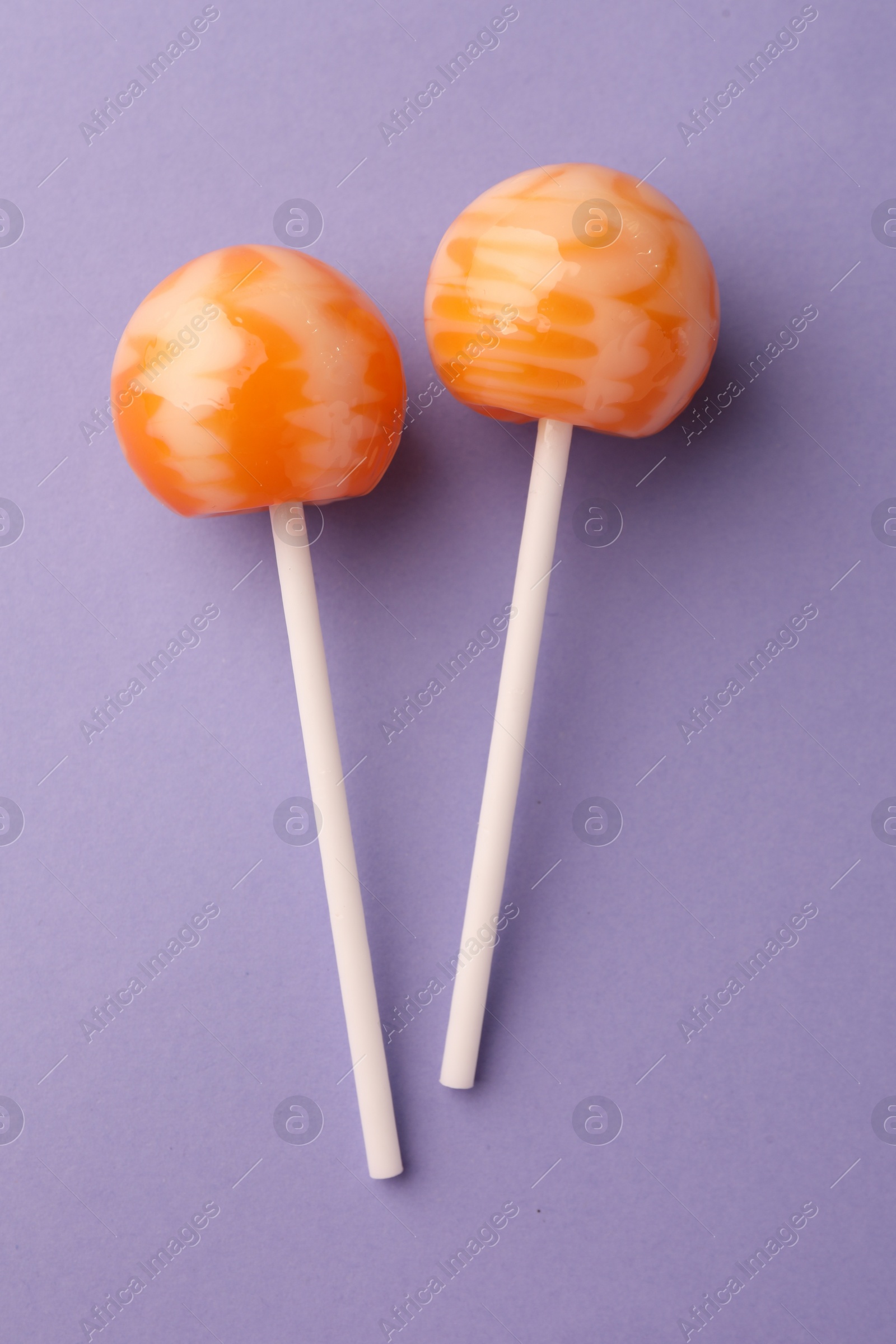 Photo of Tasty lollipops on violet background, flat lay