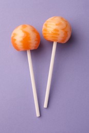 Tasty lollipops on violet background, flat lay