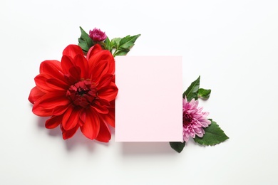 Flat lay composition with beautiful dahlia flowers and blank card on white background