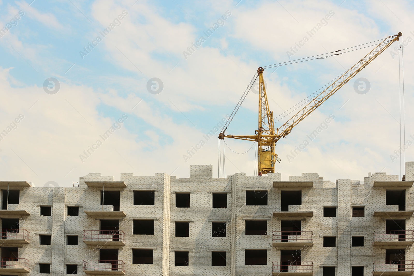 Photo of Yellow construction crane near unfinished building outdoors