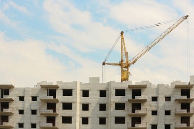 Photo of Yellow construction crane near unfinished building outdoors