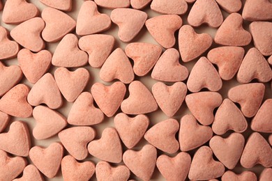 Many heart shaped vitamins for pets on beige background, flat lay