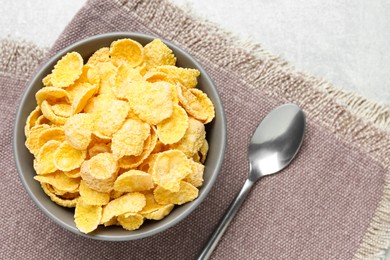 Photo of Bowl of sweet crispy corn flakes on light grey table, flat lay. Breakfast cereal
