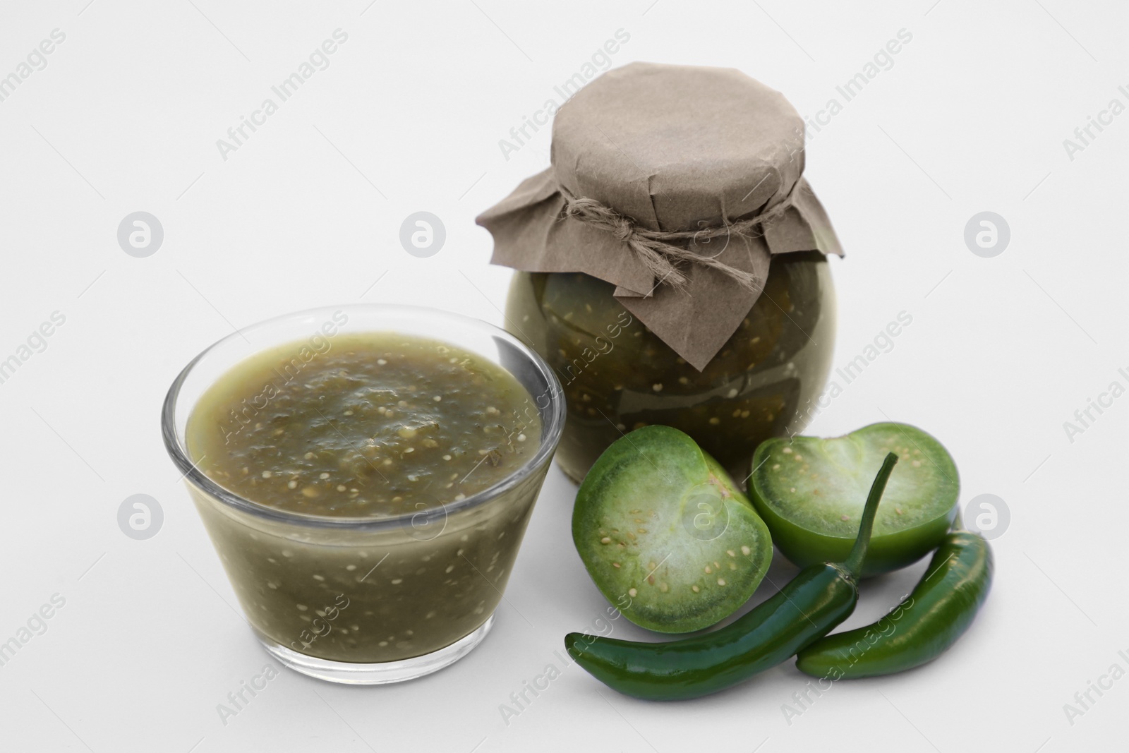 Photo of Jar with delicious salsa sauce and ingredients on white background