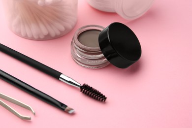 Photo of Eyebrow pomade with henna effect and professional tools on pink background