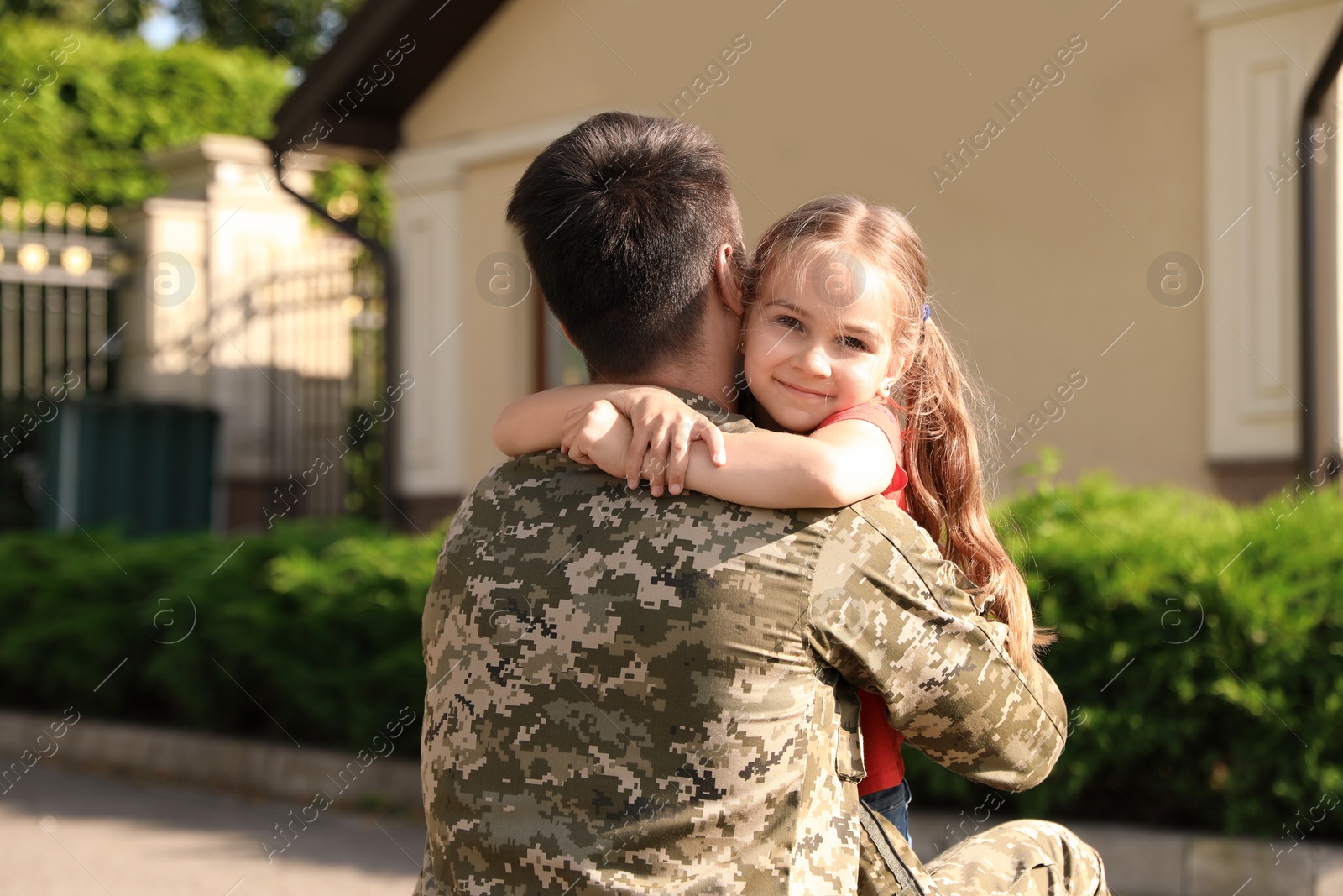 Photo of Father in military uniform hugging little daughter outdoors