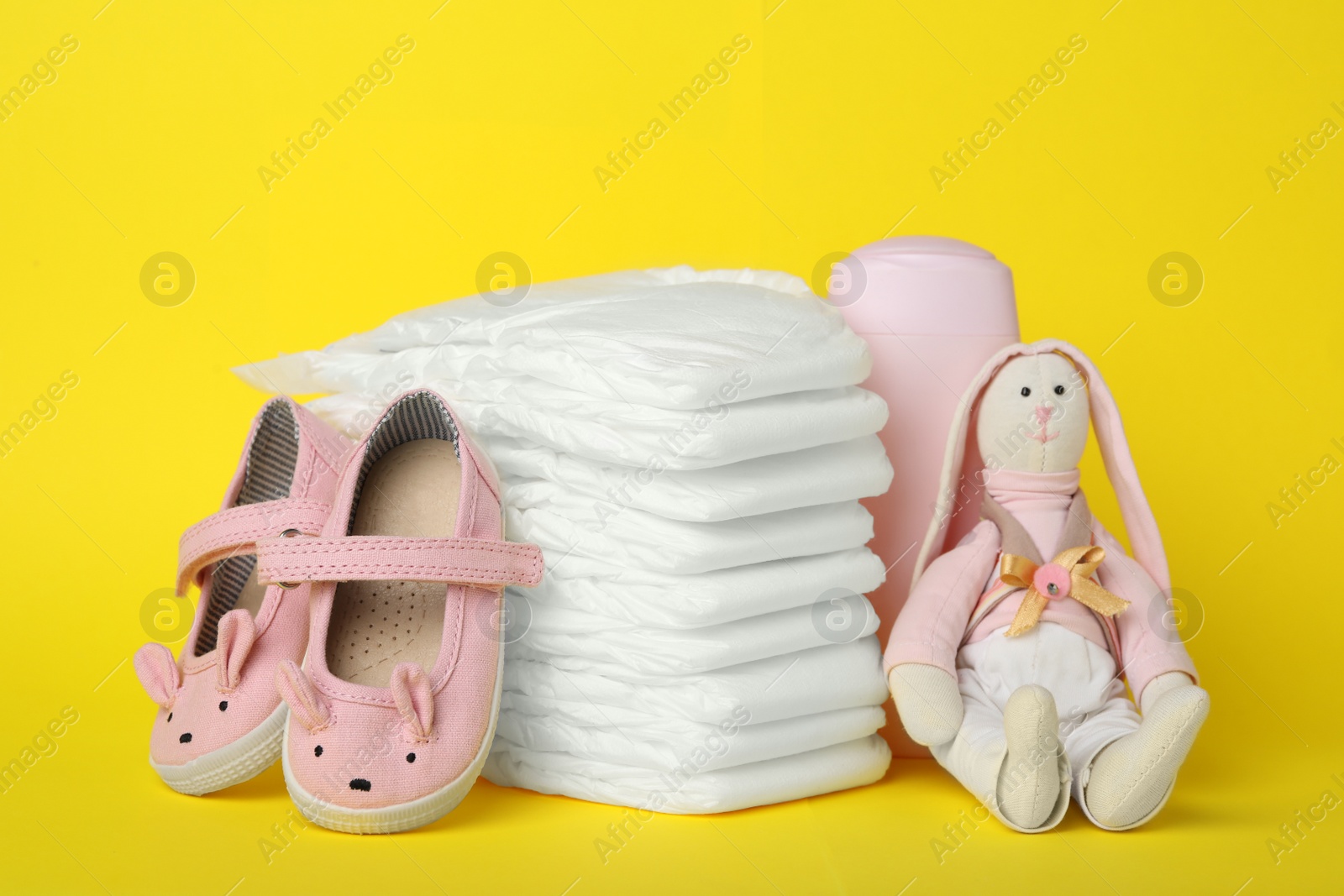 Photo of Diapers and baby accessories on yellow background
