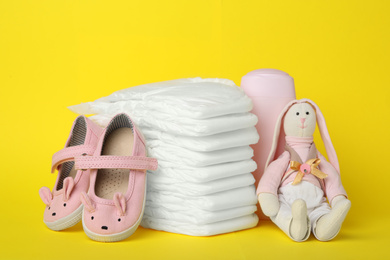 Photo of Diapers and baby accessories on yellow background
