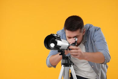 Photo of Astronomer looking at stars through telescope on orange background. Space for text