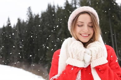 Photo of Happy young woman in warm clothes outdoors, space for text. Winter vacation