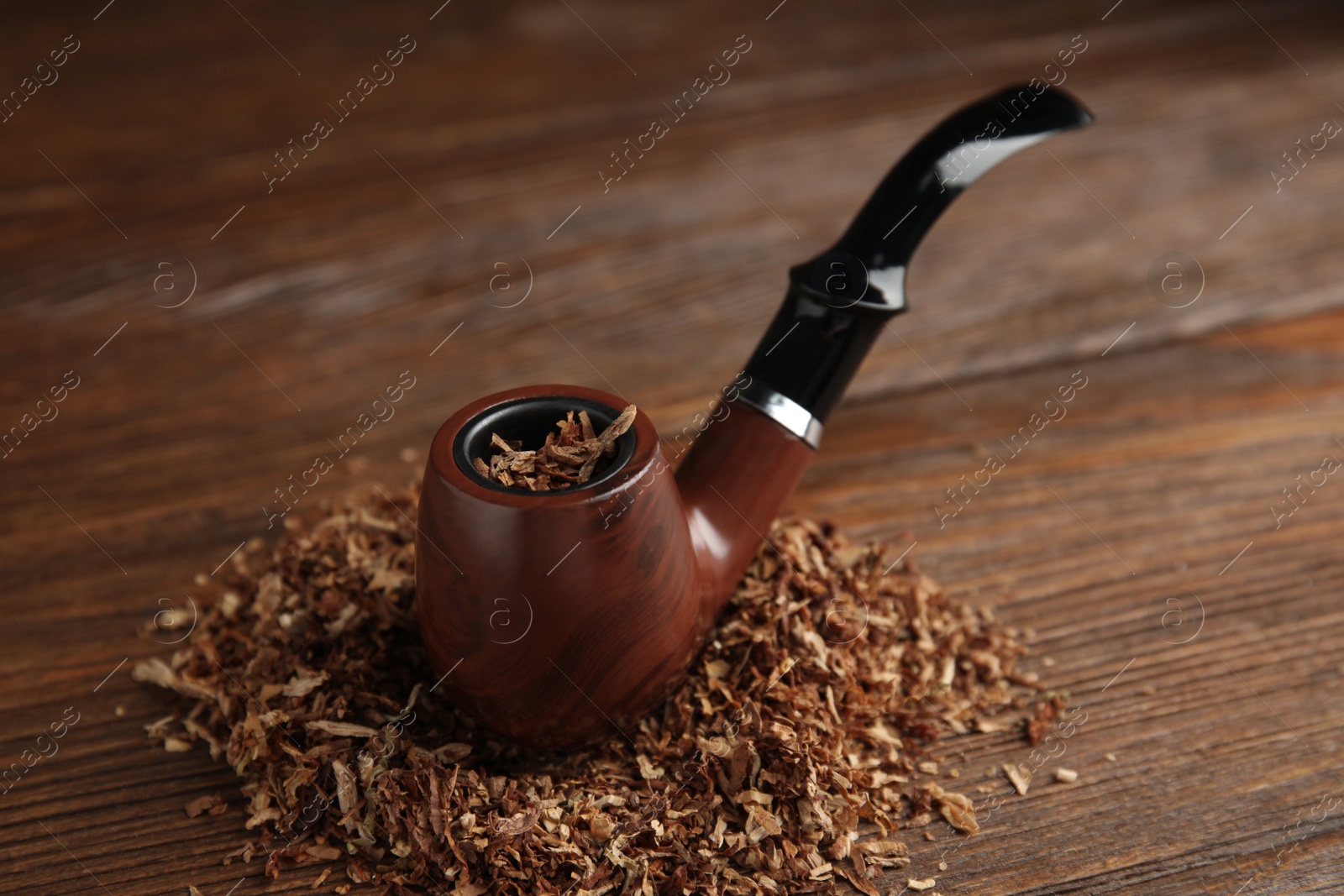 Photo of Classic smoking pipe with tobacco on wooden table