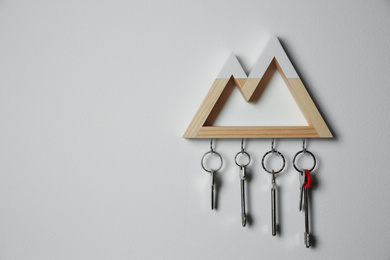 Photo of Wooden key holder on light grey wall. Space for text