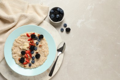Photo of Tasty oatmeal porridge with berries and almond nuts served on light table, flat lay. Space for text