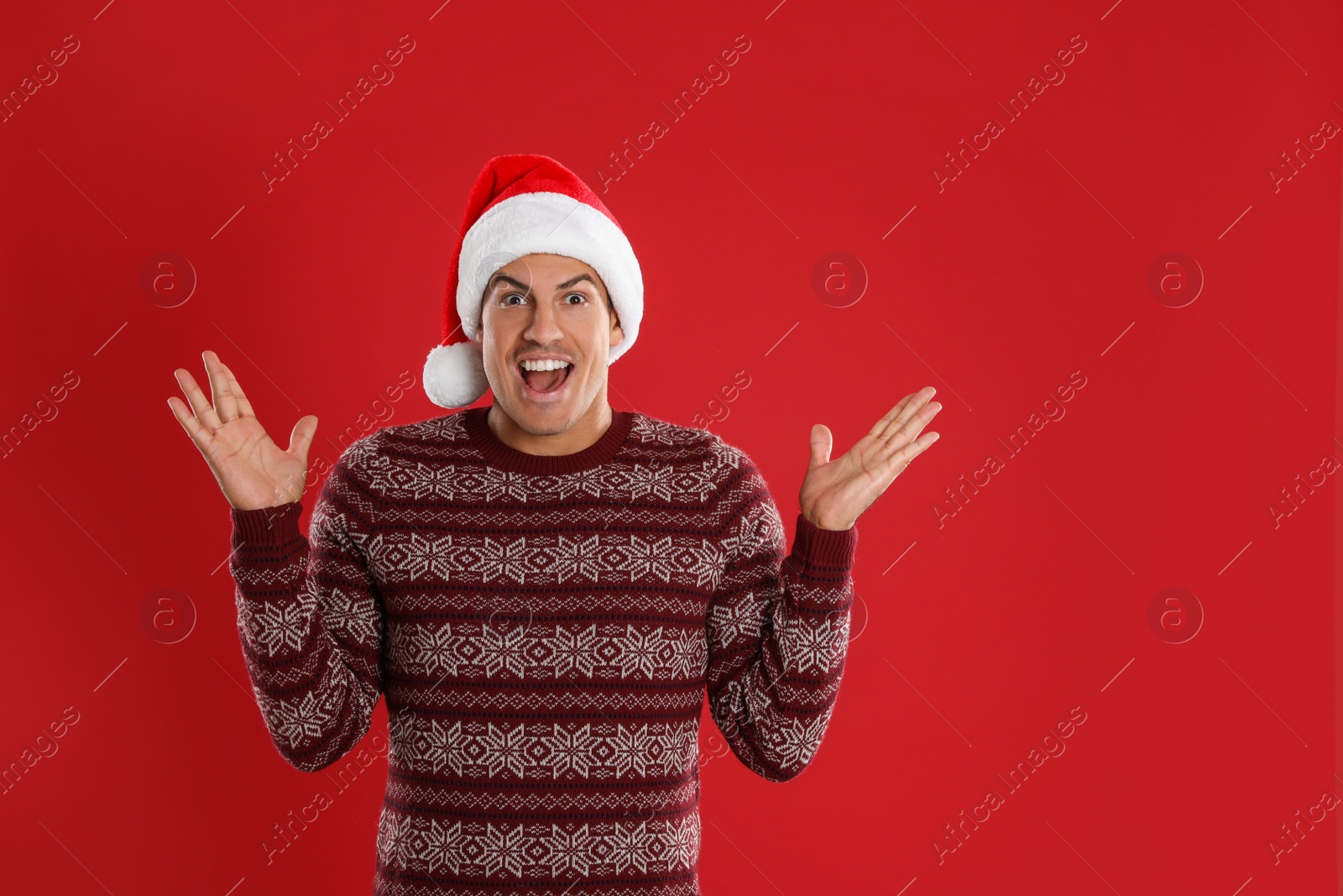 Photo of Excited man in Santa hat on red background. Christmas countdown