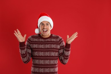 Photo of Excited man in Santa hat on red background. Christmas countdown