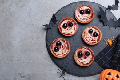 Photo of Cute monster tartlets served on grey table, flat lay with space for text. Halloween party food