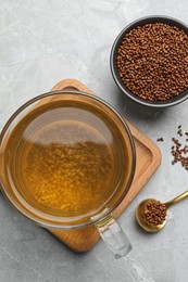 Photo of Cup of aromatic buckwheat tea and granules on light marble table, flat lay