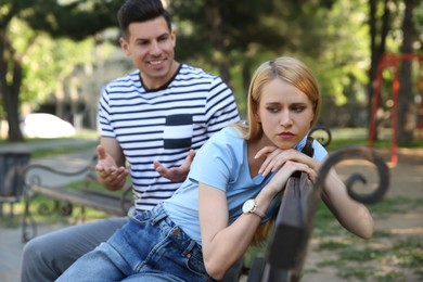 Young woman getting bored during first date with overtalkative man in park
