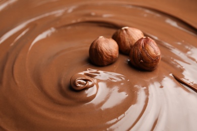 Sweet tasty chocolate cream with hazelnuts as background, closeup