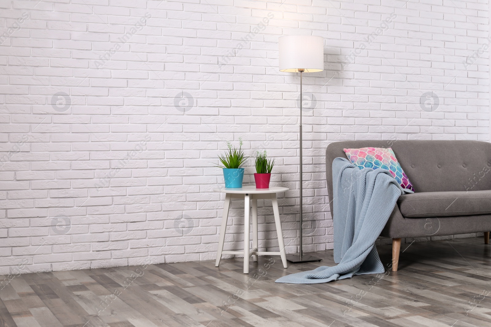 Photo of Cozy living room interior with sofa, pillow and plaid near brick wall. Space for text