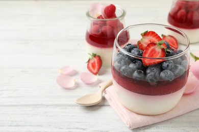 Photo of Delicious panna cotta with berries on white wooden table. Space for text