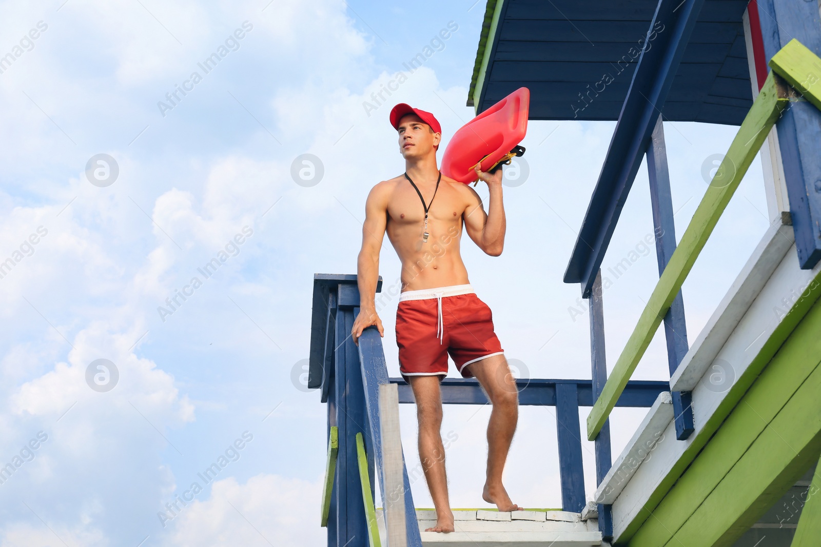 Photo of Handsome lifeguard with life buoy on watch tower