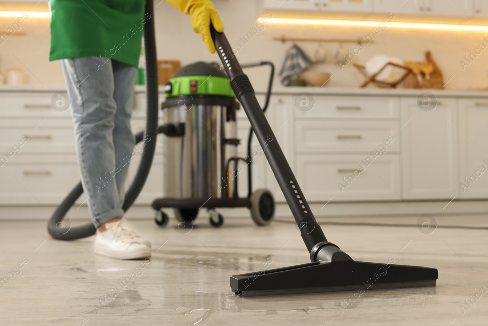 Photo of Professional janitor vacuuming floor in kitchen, closeup