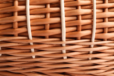 Handmade wicker basket made of natural material as background, closeup view