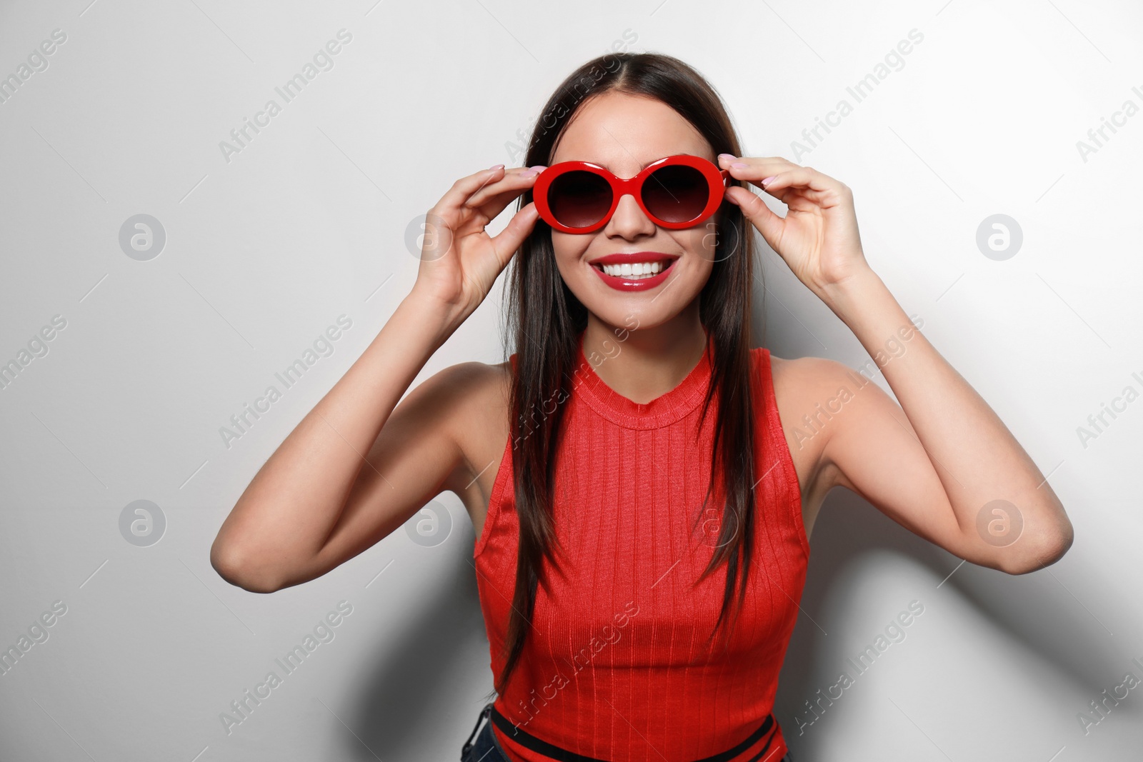 Photo of Beautiful woman in stylish sunglasses on light background