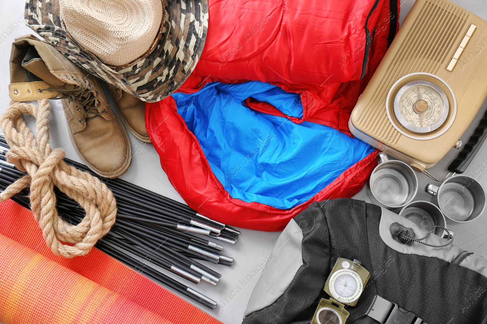 Photo of Flat lay composition with sleeping bag and camping equipment on grey background