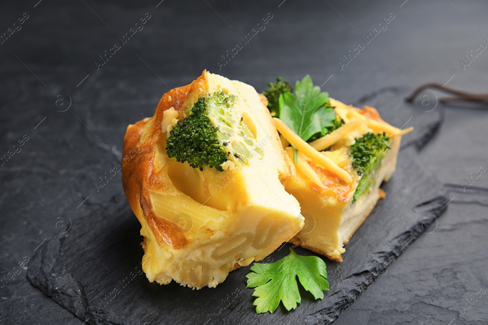 Photo of Tasty broccoli casserole served on black table, closeup