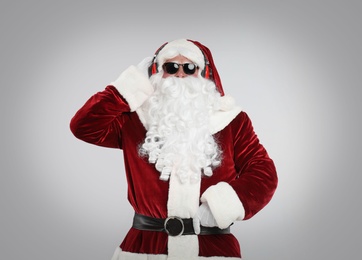 Photo of Santa Claus with headphones listening to Christmas music on light grey background