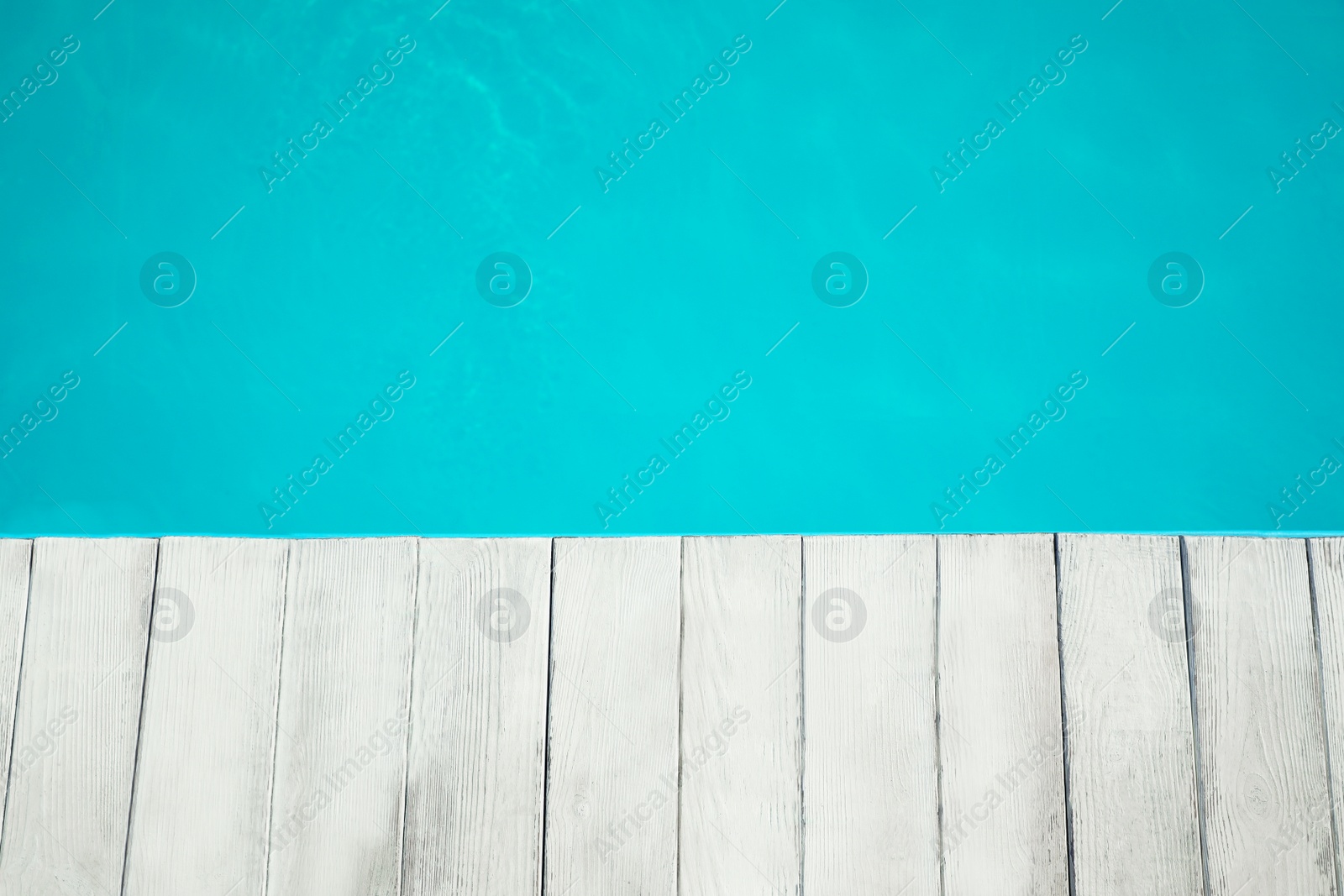 Photo of Wooden deck near swimming pool outdoors, top view. Space for text