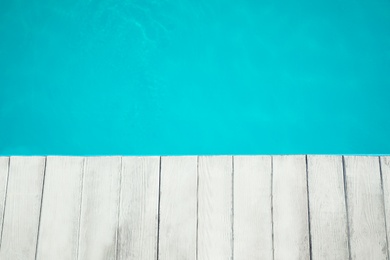 Photo of Wooden deck near swimming pool outdoors, top view. Space for text