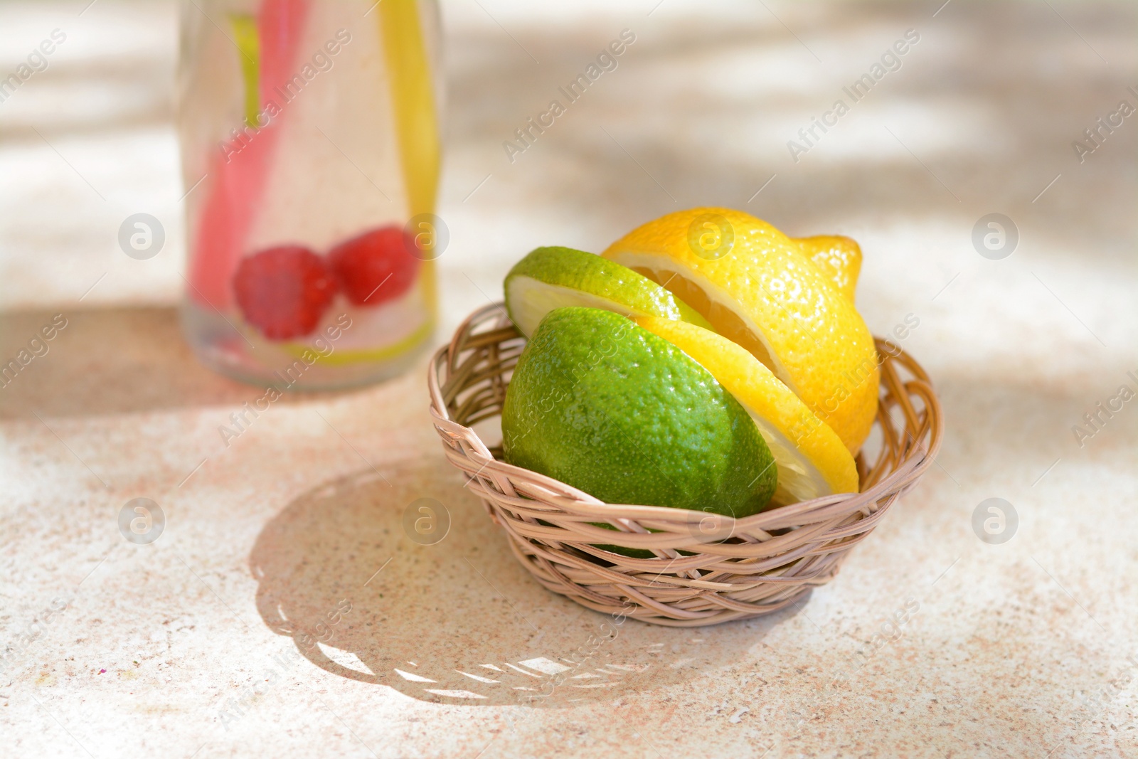 Photo of Basket with fresh citrus fruits on beige table, closeup