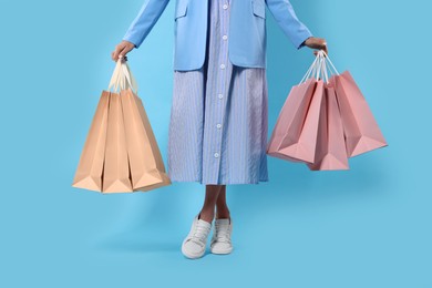 Photo of Woman with shopping bags on light blue background, closeup