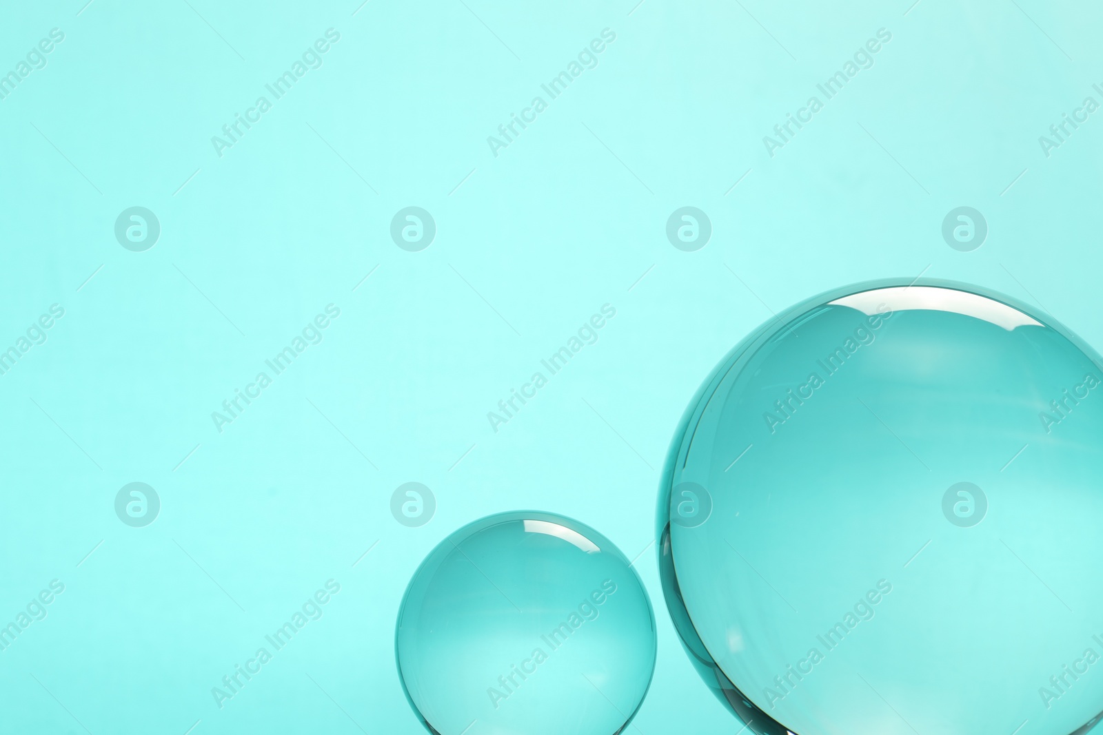 Photo of Transparent glass balls on turquoise background. Space for text