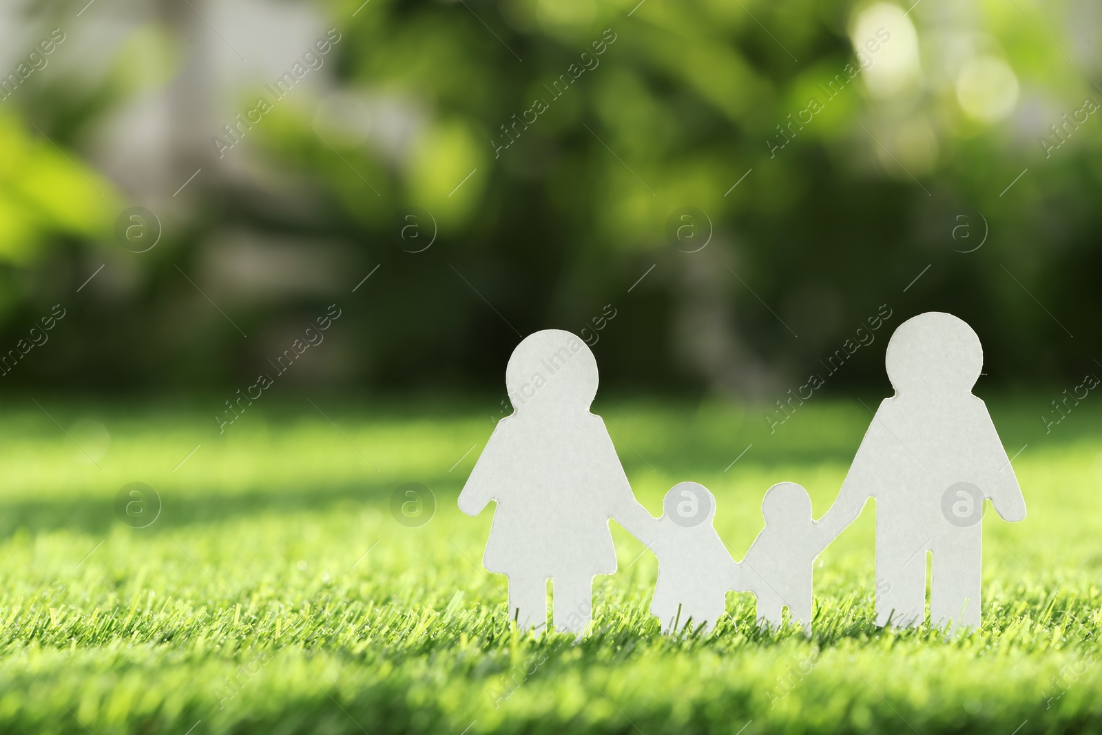 Photo of Paper cutout of family on fresh grass, space for text. Life insurance concept