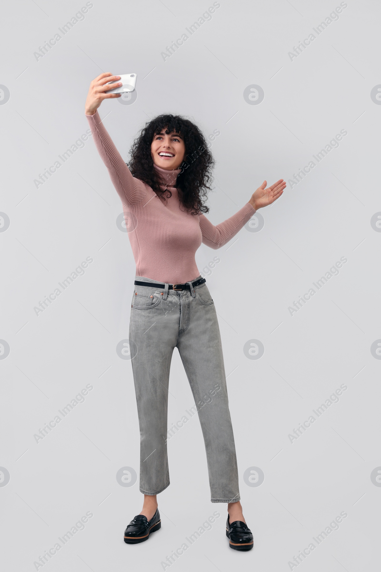 Photo of Beautiful young woman taking selfie on light grey background