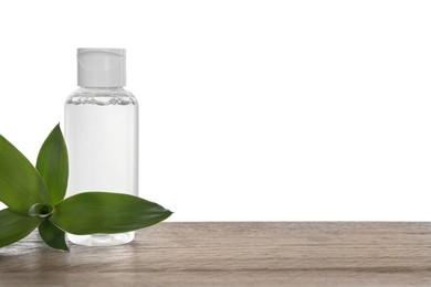 Photo of Micellar water in bottle and green plant on wooden table against white background. Space for text