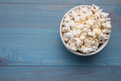 Photo of Tasty popcorn on light blue wooden table, top view. Space for text