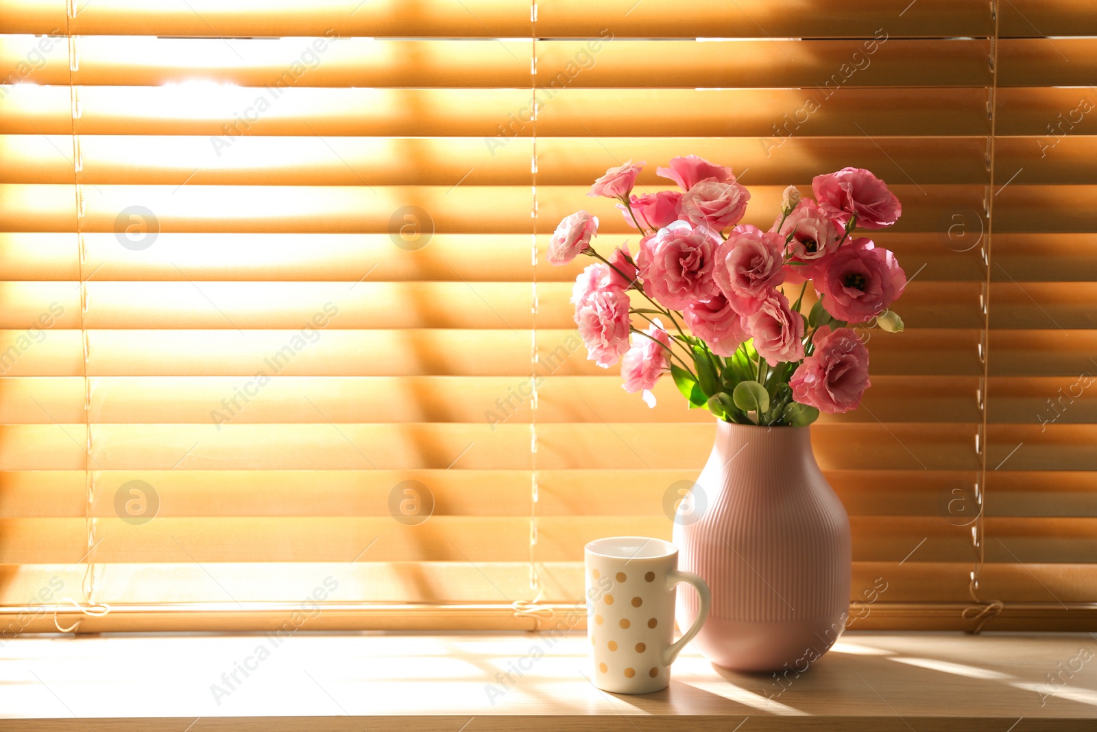 Photo of Vase with flowers and cup on wooden window sill in room, space for text