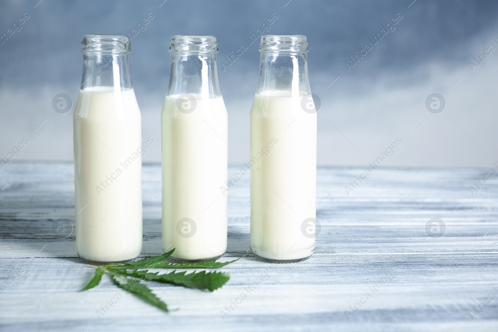 Photo of Glass bottles with hemp milk on table