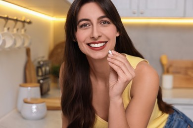 Photo of Beautiful woman taking vitamin pill at home