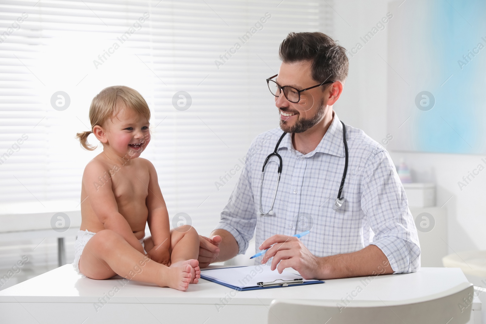 Photo of Pediatrician examining cute little baby in clinic