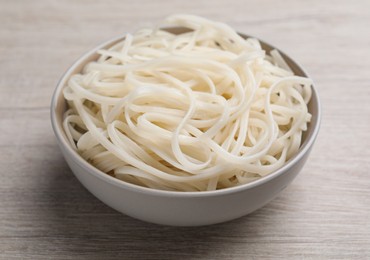 Photo of Bowl of tasty cooked rice noodles on white wooden table