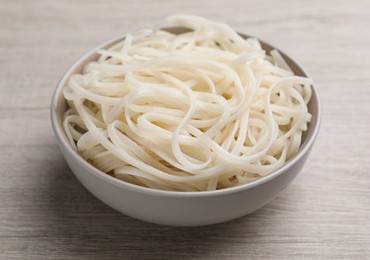 Bowl of tasty cooked rice noodles on white wooden table